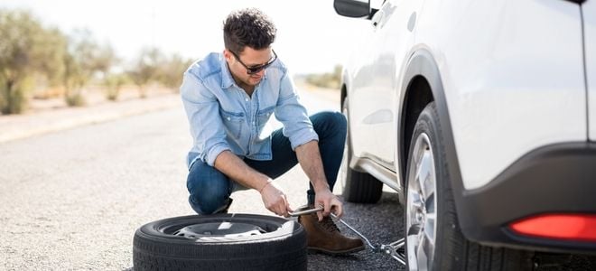 a man cranking a car jack to change his tire