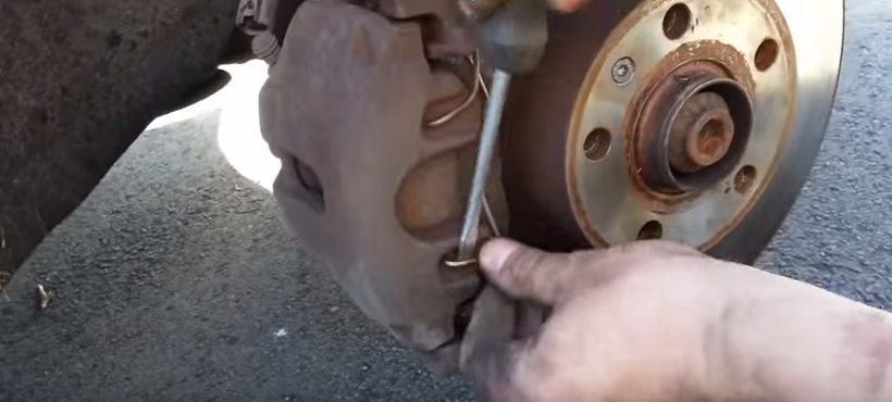 Removing metal clip to remove brake pads
