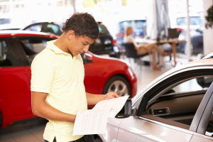 Young man looking at paperwork in a dealership.