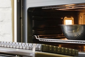 an oven open on a white brick wall