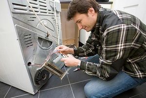 A technician working on repairing issues with a dryer.