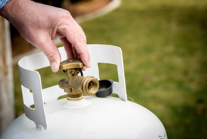 hand twisting the control valve on a propane tank