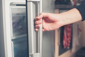 A person opening a refrigerator door.