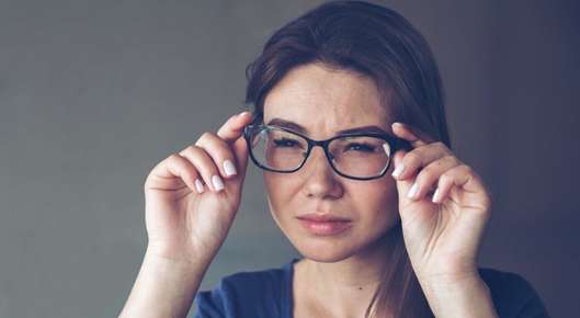 Image of an optometrist helping a patient try on a pair of glasses.