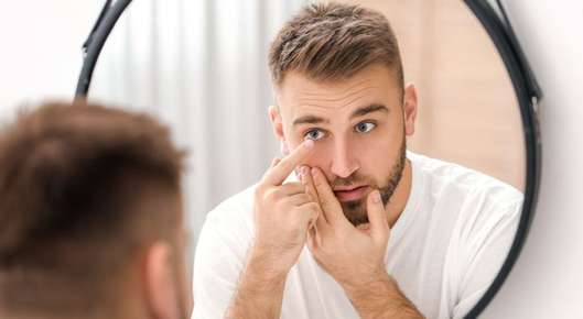Image of a man holding a contacts lens.
