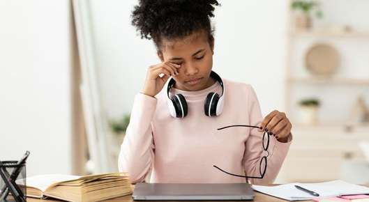 teen rubs eye while reading