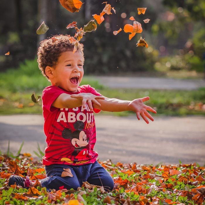 child playing in autumn leaves