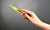 A woman's hand holding up a yellow utility knife.
