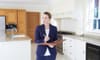 A female realtor standing in a kitchen with a clipboard.
