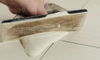 hand applying tile grout with a scraper
