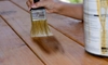 Use a paintbrush to stain a wooden deck.