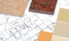 A collection of paint chips and granite samples over a home's blueprint. 