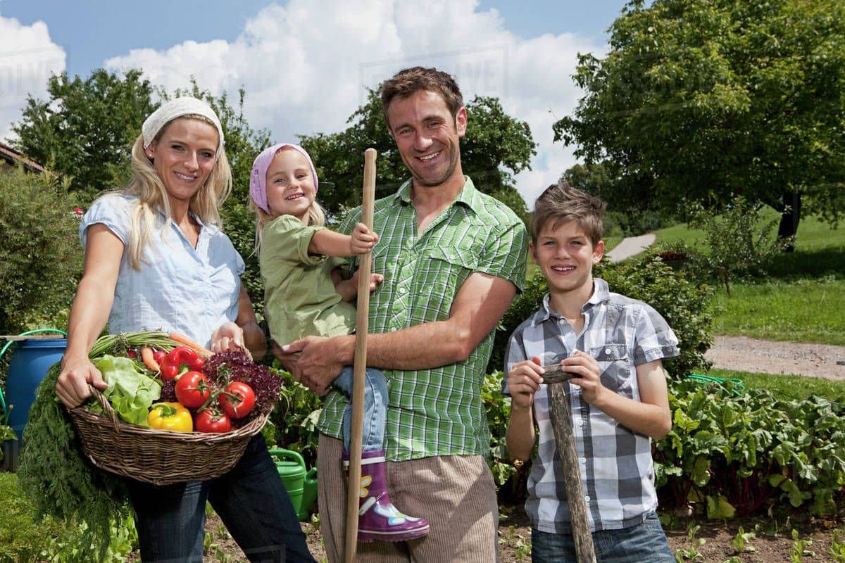 Family in garden holding basket of vegetables