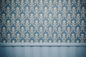 a wall with winscotting on the bottom and blue and tan wallpaper on the top