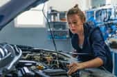 woman working under car hood in auto shop