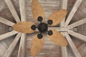A view looking up at a rustic wood ceiling with a bamboo ceiling fan.