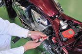 A person performing basic maintenance on a red motorcycle.