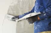 A DIYer plastering a concrete wall.