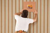 man hanging artwork on a wallpapered wall