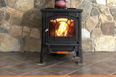 small wood stove on hearth pad in front of stone wall