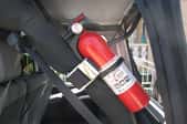 A fire extinguisher secured in the trunk of a vehicle.