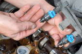 two hands holding fuel injectors