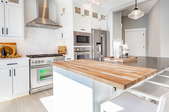 clean white kitchen with butcher block island countertop