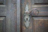 A wood door with a decorative handle.
