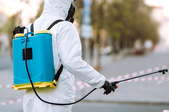 person in protective suit with backpack spray cleaner