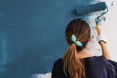woman painting blue wall with roller
