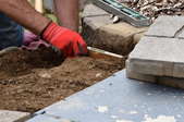hands with gloves installing paver patio steps