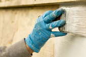 gloved hand painting house exterior
