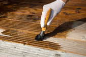 A darker stain being painted on a deck.