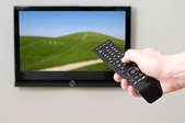 Hand holding a remote aimed at a TV