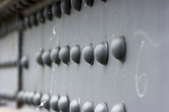 Several rows of solid rivets used to fasten a metal girder.