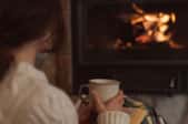 woman with cup in front of gas fireplace with low flame