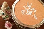 A mason jar lid embossed with a reindeer. 