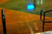 a shiny concrete floor next to stair railings with colorful angular shapes