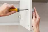 screwing a handle onto a white cabinet