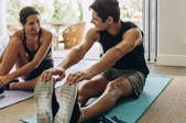 smiling woman and man stretching on yoga mats