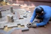 man laying hardscape bricks in pattern