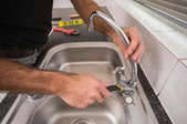 A man replacing a sink faucet.