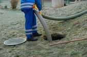 man with hose pumping out a septic tank