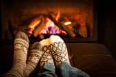 A pair of socked feet in front of a fire.