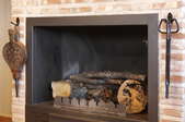 A brick fireplace with tools on either side of it.
