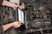 A pair of hands replacing an air filter in a car. 