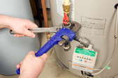 A pipe and crescent wrench adjusting a valve on a water heater.