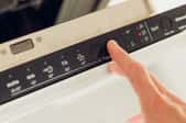 hand pressing buttons on dishwasher control panel