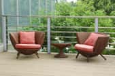 Two outdoor wicker chairs covered with seat cushions.