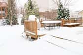A snow-covered deck in a yard. 